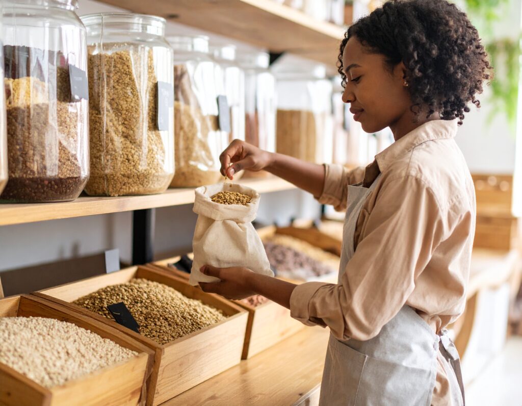 over-the-shoulder view of a woman filling a reusable cotton bag with dried lentils in 860545